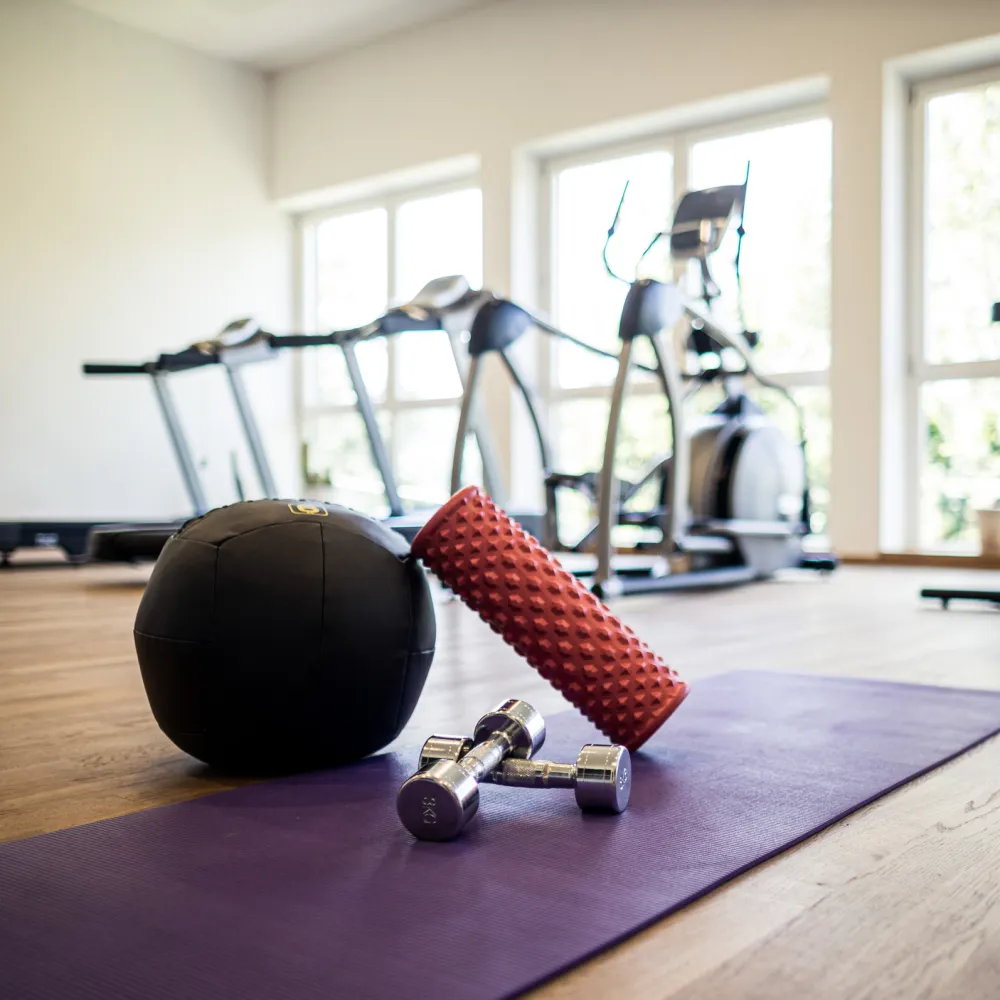 Palla medica, foam roller e tappetino davanti agli attrezzi nella palestra del Wellnesshotel Alpenflora