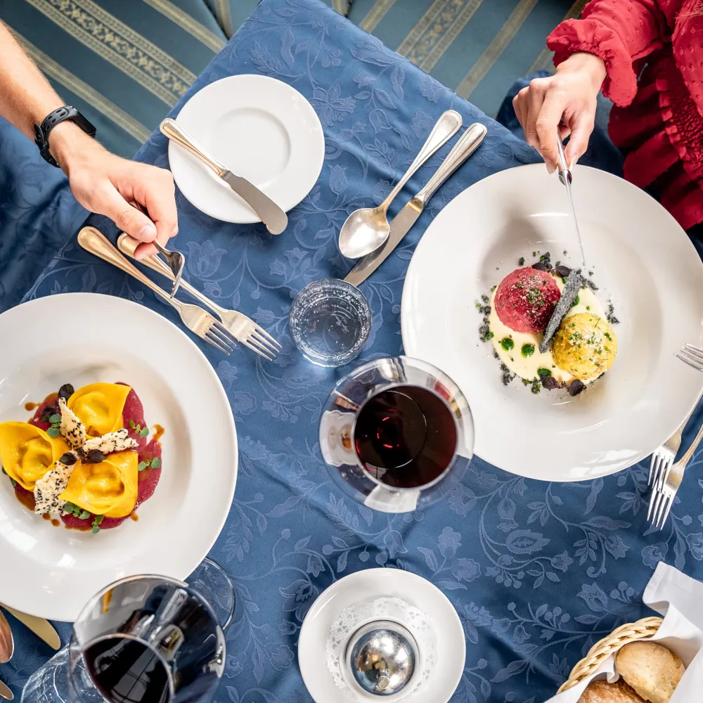 Gedeckter Tisch im Alpenflora mit fein angerichteten Gerichten und Südtiroler Wein