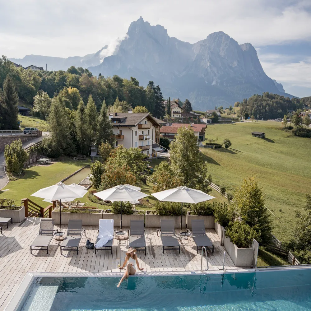 Piscina esterna con ombrelloni e vista sulle Dolomiti all’Alpenflora