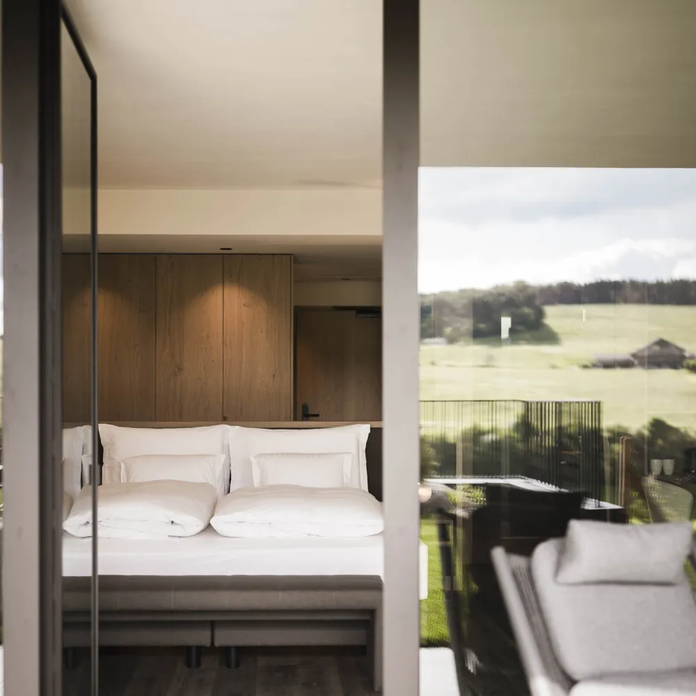 Hotelzimmer im Alpenflora mit Holzelementen und Panoramafenster zur Bergwiese