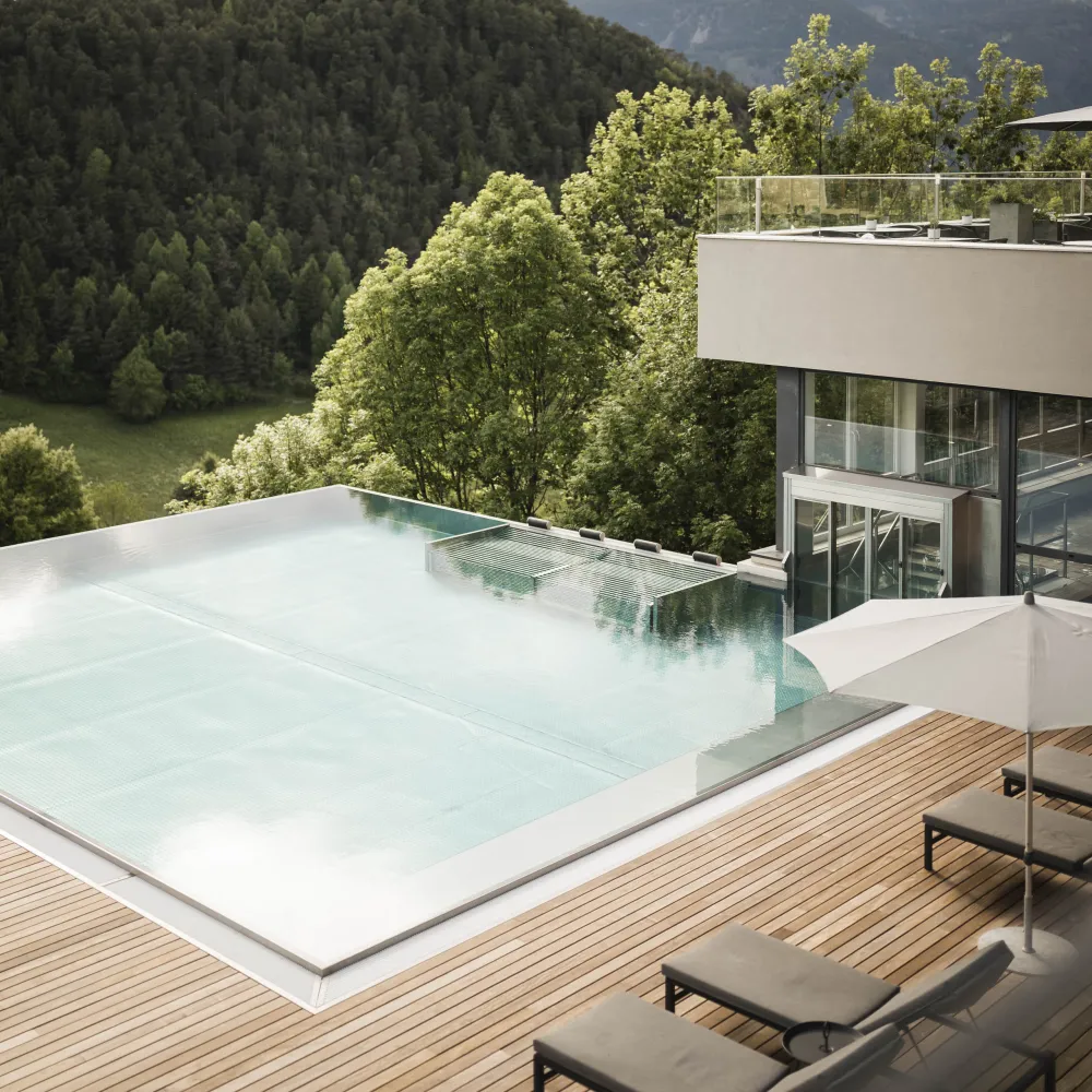 Infinity Pool on the wooden terrace of the Wellness Hotel Alpenflora overlooking forest and mountains
