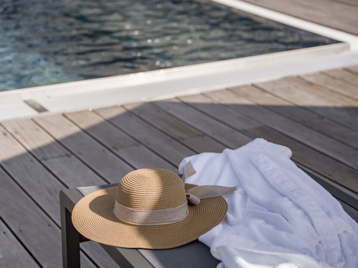 Strohhut und Bademantel auf einer Liege am Pool des Wellnesshotels Alpenflora in Kastelruth