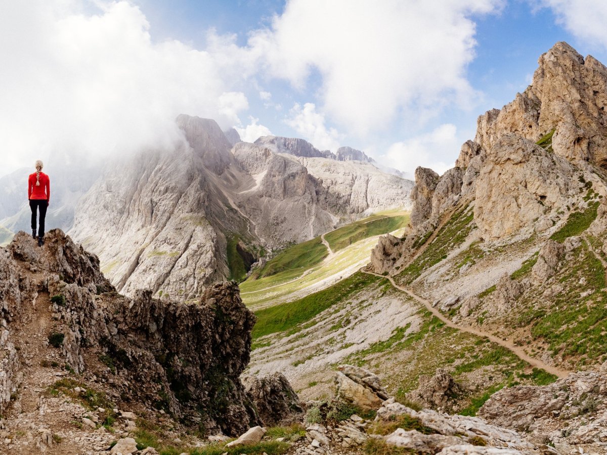 Wanderin auf einem Felsgrat mit weitem Blick über das Dolomitenpanorama