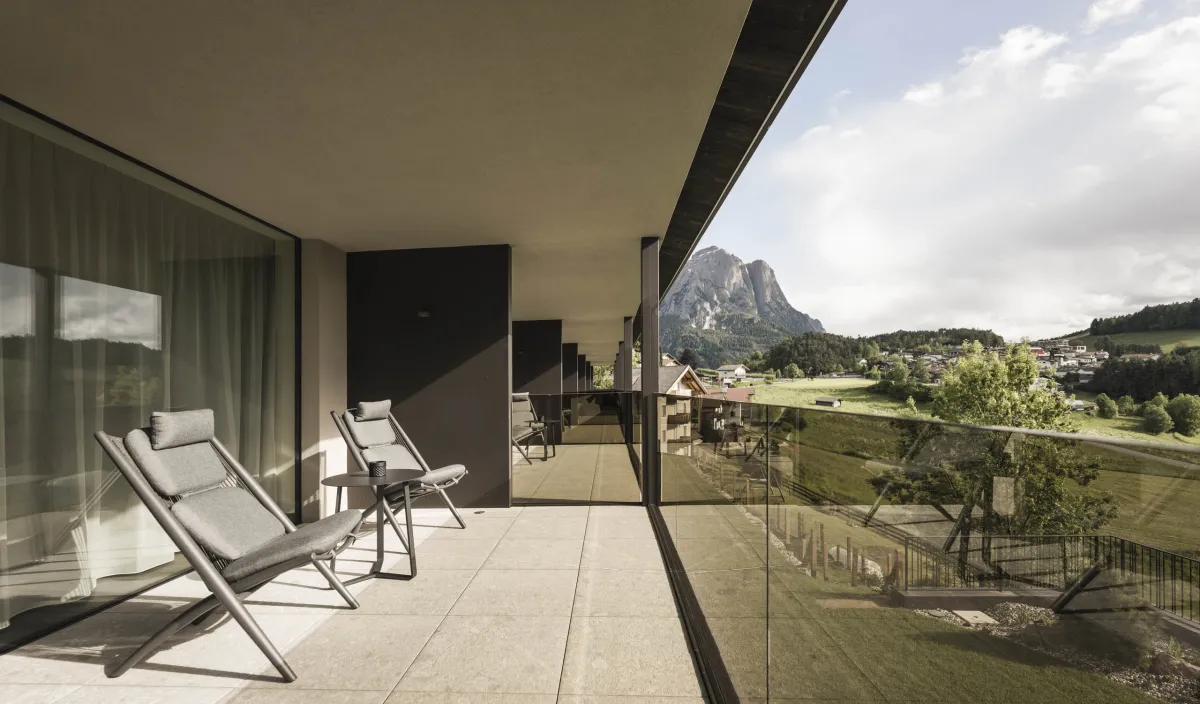Balkon mit zwei Liegestühlen und Blick auf die Berge und das Dorf vom Zimmer Garden View.