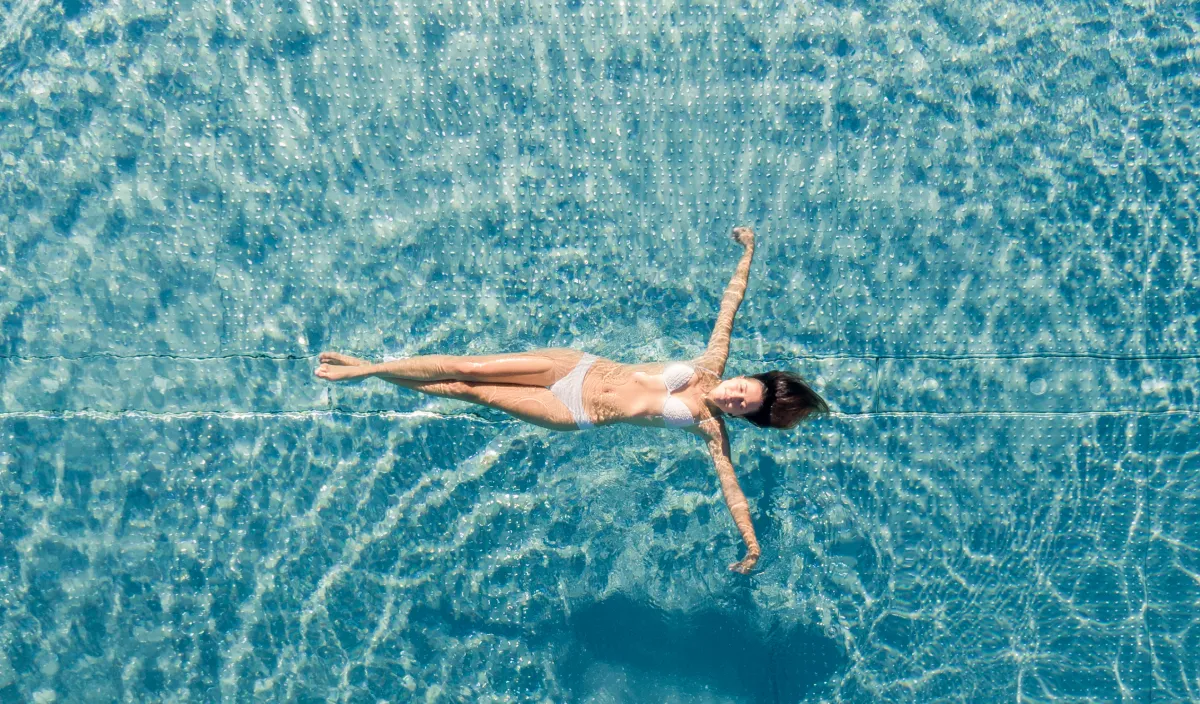 Person swimming in the turquoise pool of the Wellness Hotel Alpenflora seen from above