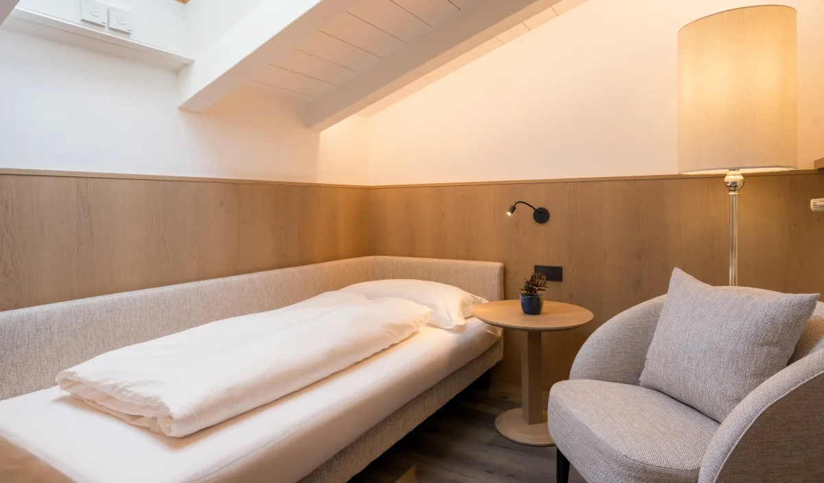 Zusätzlicher Schlafbereich unter der Dachschräge mit Einzelbett, Sessel und Dachfenster.