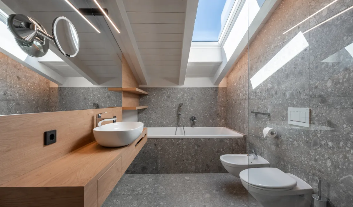 Badezimmer mit Waschtisch, Badewanne, Bidet, WC und Dachfenster mit Tageslicht in der Attico Suite.