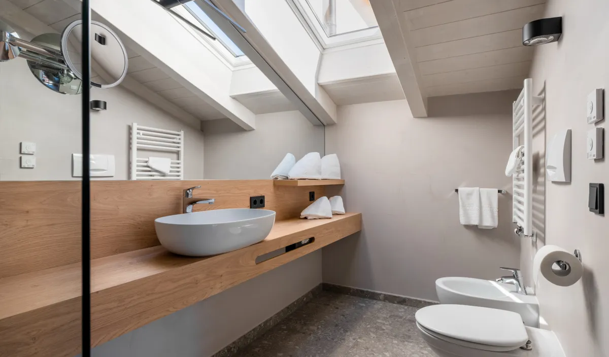 Badezimmer unter der Dachschräge mit Waschtisch auf Holzplatte, Bidet, WC und Dachfenster.