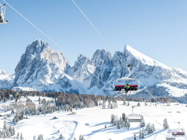 Chairlift in front of the snow-covered peaks of the Dolomites above the wintry Alpe di Siusi