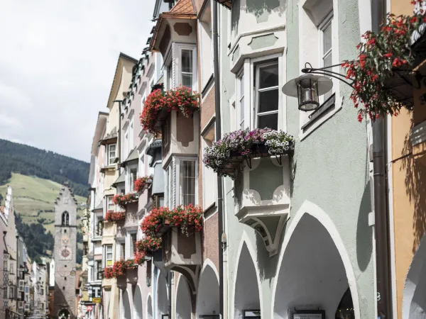 Lane with flower-decked bay windows and a town tower in South Tyrol