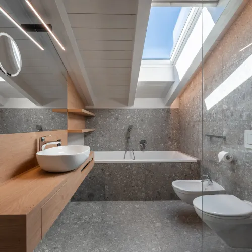 Bathroom with vessel sink on wooden vanity, bathtub, bidet, WC and skylight with blue sky.
